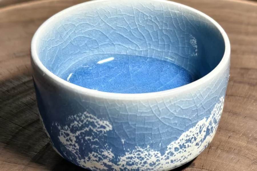 A blue-glazed ceramic cup with a crackled surface on a wooden table